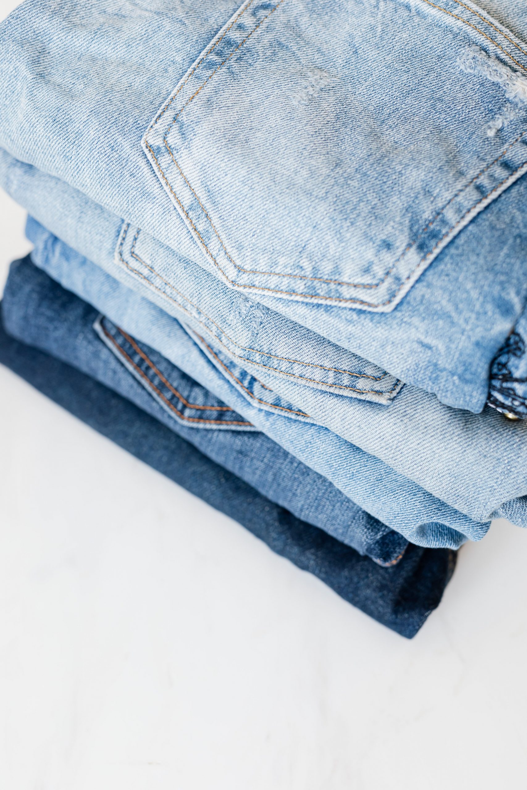 stack-of-jeans-on-white-marble-surface-4210857